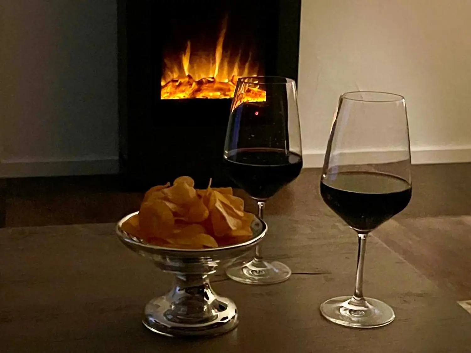 DE SUITE – Winterberg Deluxe, 2 wijnglazen en chips op tafel bij de open haard