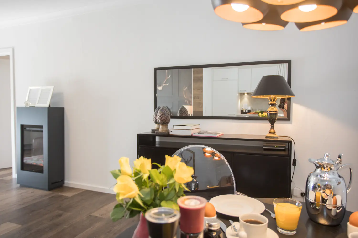 DE SUITE – Winterberg Deluxe, ontbijtservies op tafel en kaptafel en spiegel aan de muur op de achtergrond