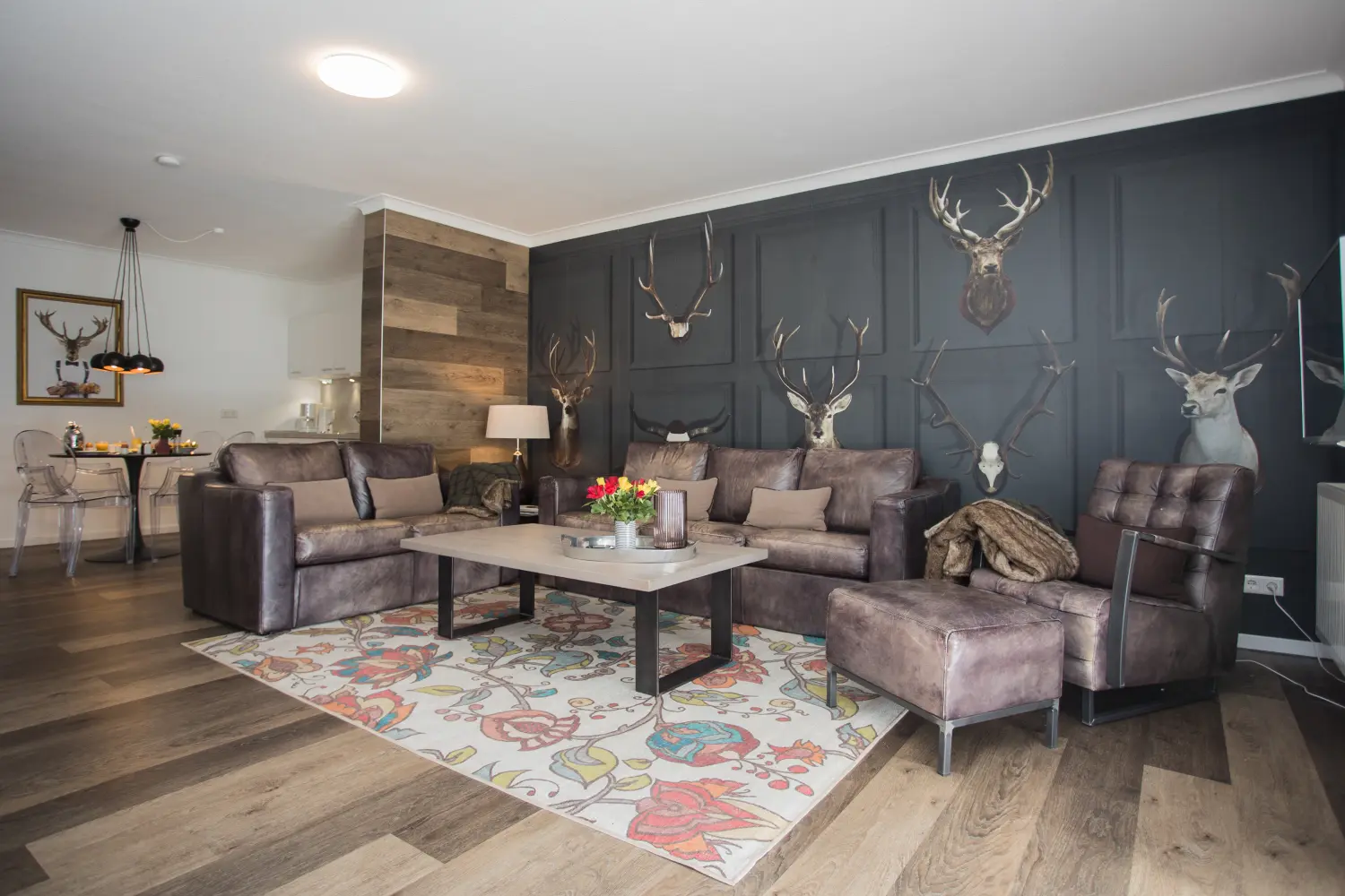 DE SUITE – Winterberg Deluxe, woonkamer, met toneelhoorns en toneelhoofddecoratie aan de muur.